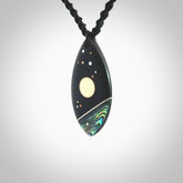 This photo shows a medium sized drop pendant hand carved from Ebony wood with Mother of Pearl and Paua Shell inlay, alongside; brass, copper and silver. This is a stand out one off necklace for those who appreciate art to wear. It is provided with a cord in black that is a fixed length with Paua Shell Toggle. We ship this piece worldwide and shipping is included in the price.